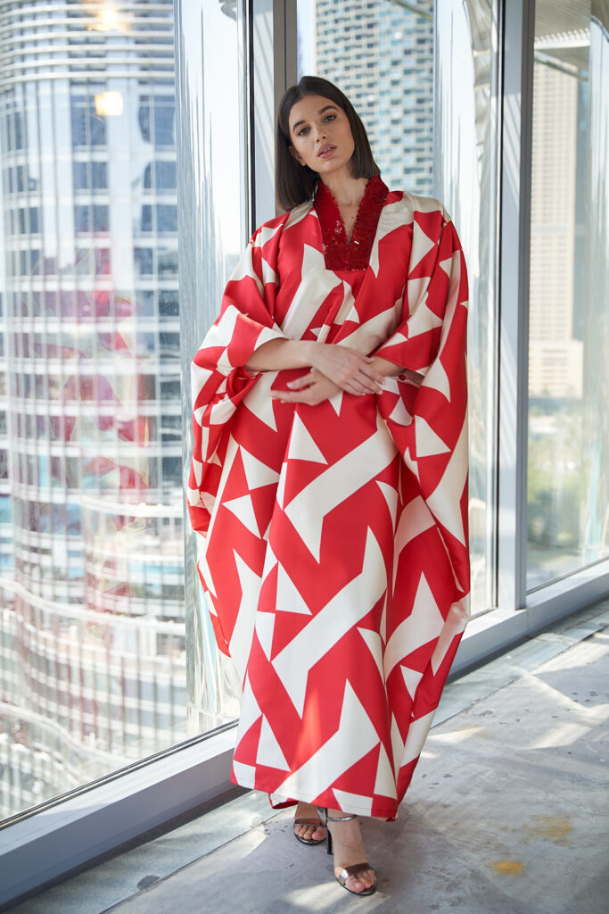 Model in white and red Anaya Abaya with Downtown Dubai backdrop.