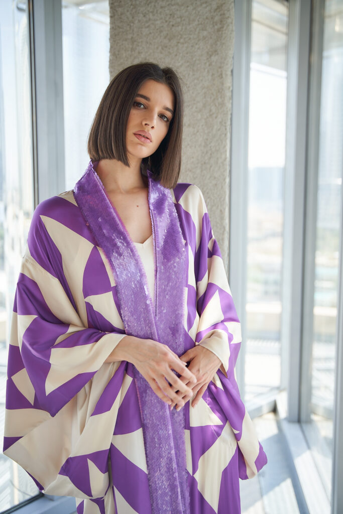 Model in white and violet abaya with geometric design
